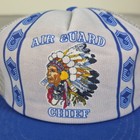 White 1980s US Air Force Indian Chief trucker hat with blue/white chevron logo and embroidered feathered headdress.
