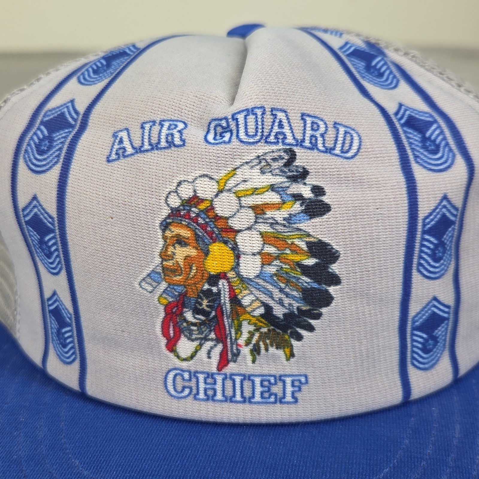 White 1980s US Air Force Indian Chief trucker hat with blue/white chevron logo and embroidered feathered headdress.