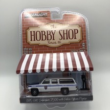 2024 GREENLIGHT 1985 GMC SUBURBAN 2500 WITH POLICE OFFICER HOBBY SHOP SERIES 16