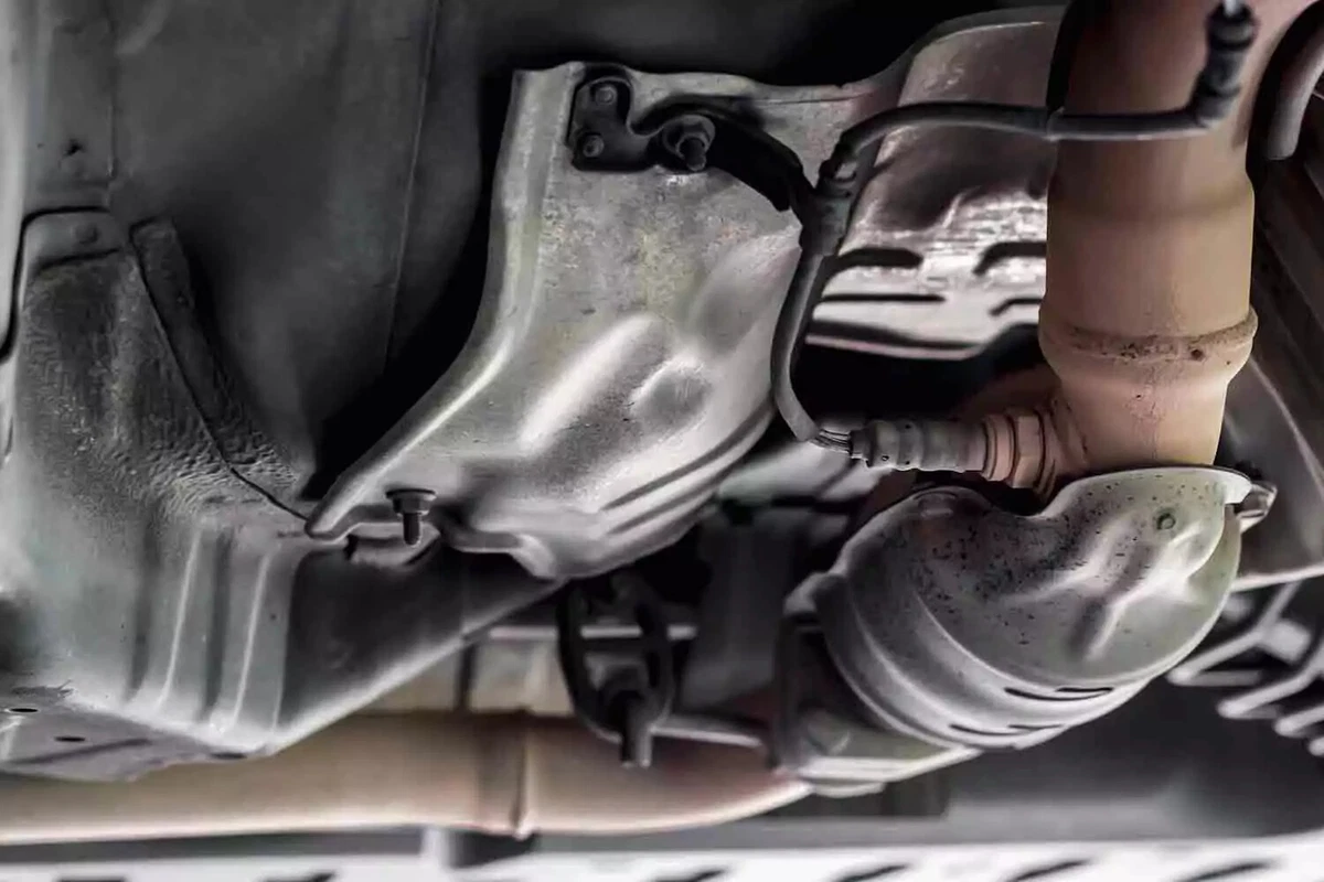 A downstream oxygen sensor in a vehicle exhaust next to the heat-shielded catalytic converter.