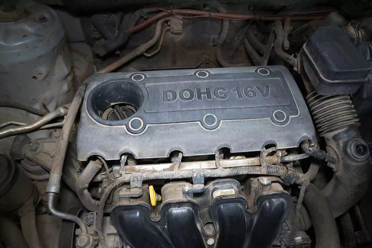 Engine bay showing spark plugs obscured by an ornamental plastic engine cover.