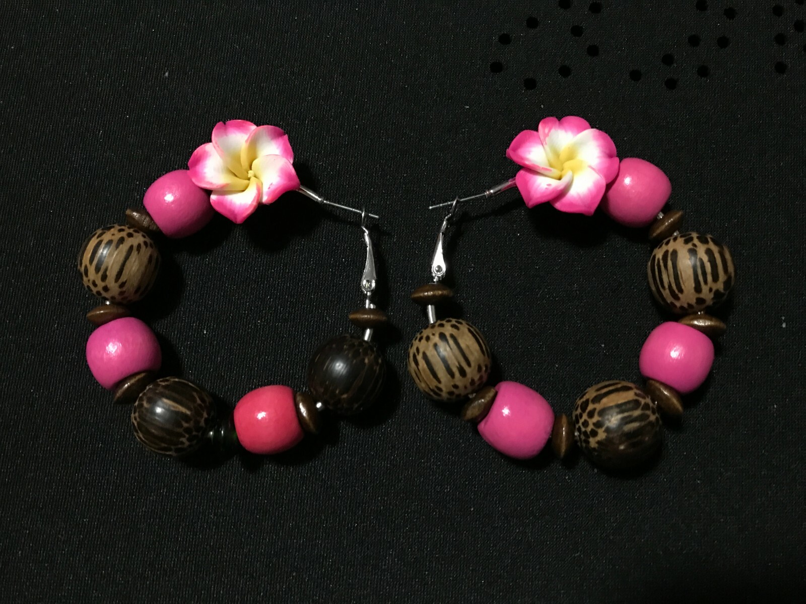 Artisan-made wood hoop earrings adorned with vibrant plastic flowers-image