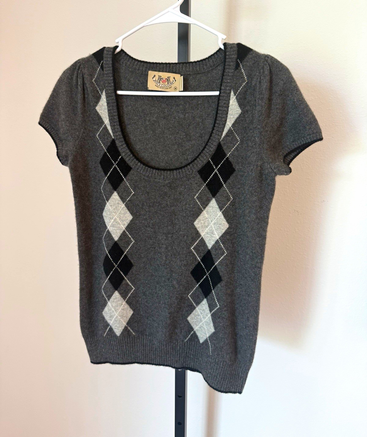 Gray argyle cashmere short-sleeve sweater on a hanger.