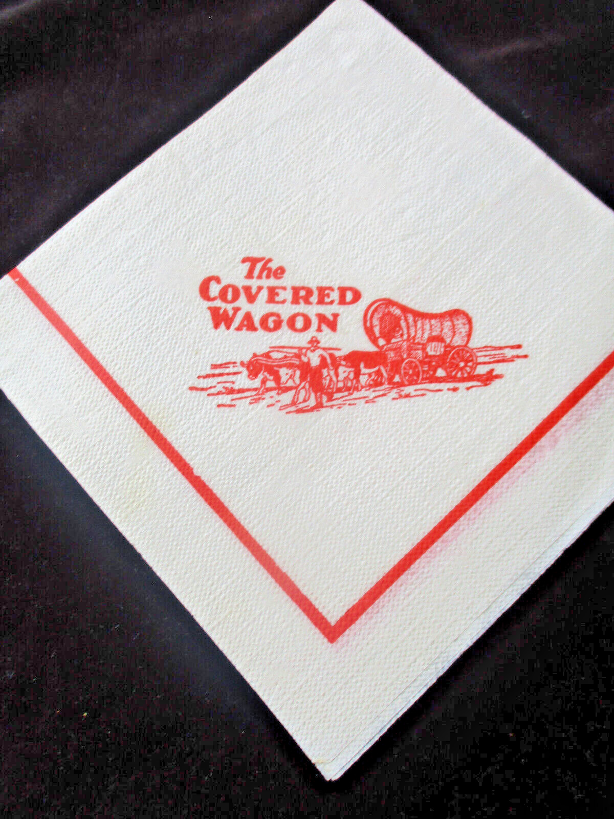 Vintage THE COVERED WAGON AD on Crepe Paper Napkin / Restaurant? Red on White