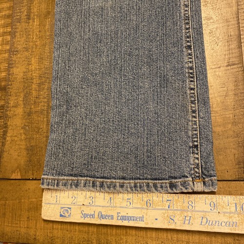 Blue Theory jeans, 30x33, with faded front seam detailing, laid flat on wooden ruler labeled “Speed Queen Equipment.”