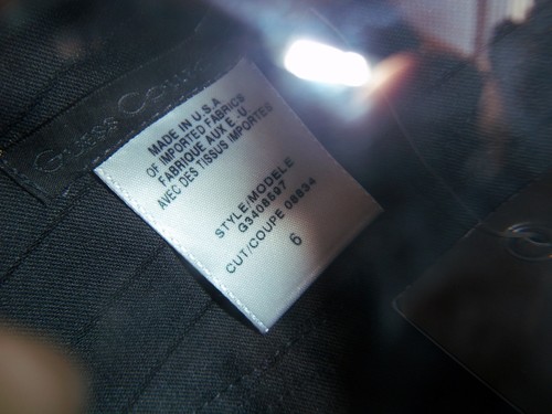 White Guess collection tag on black fabric, size 6, with product details and “MADE IN U.S.A.” text.