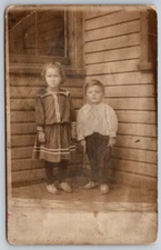 2 Children Girl and Boy Pictured On Front Porch Of Their House RPPC Postcard