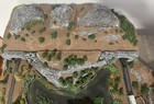 Z scale model layout with rocky cliffs, river, trees, and train tracks passing through a natural gorge.