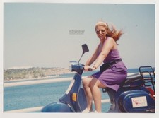 Strahlende junge Frau auf Vespa am Meer windgeblasene Haare Vintage...