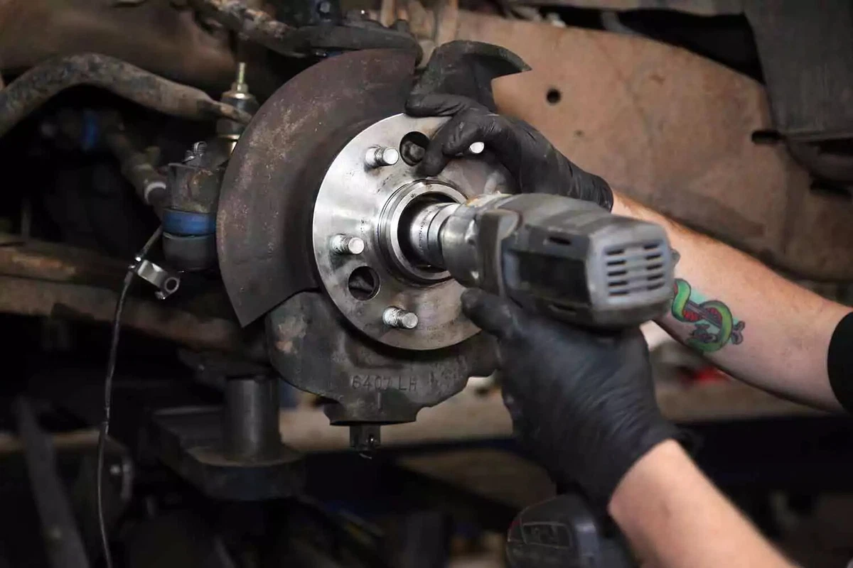 A mechanic reinstalls the splash shield in its original location.