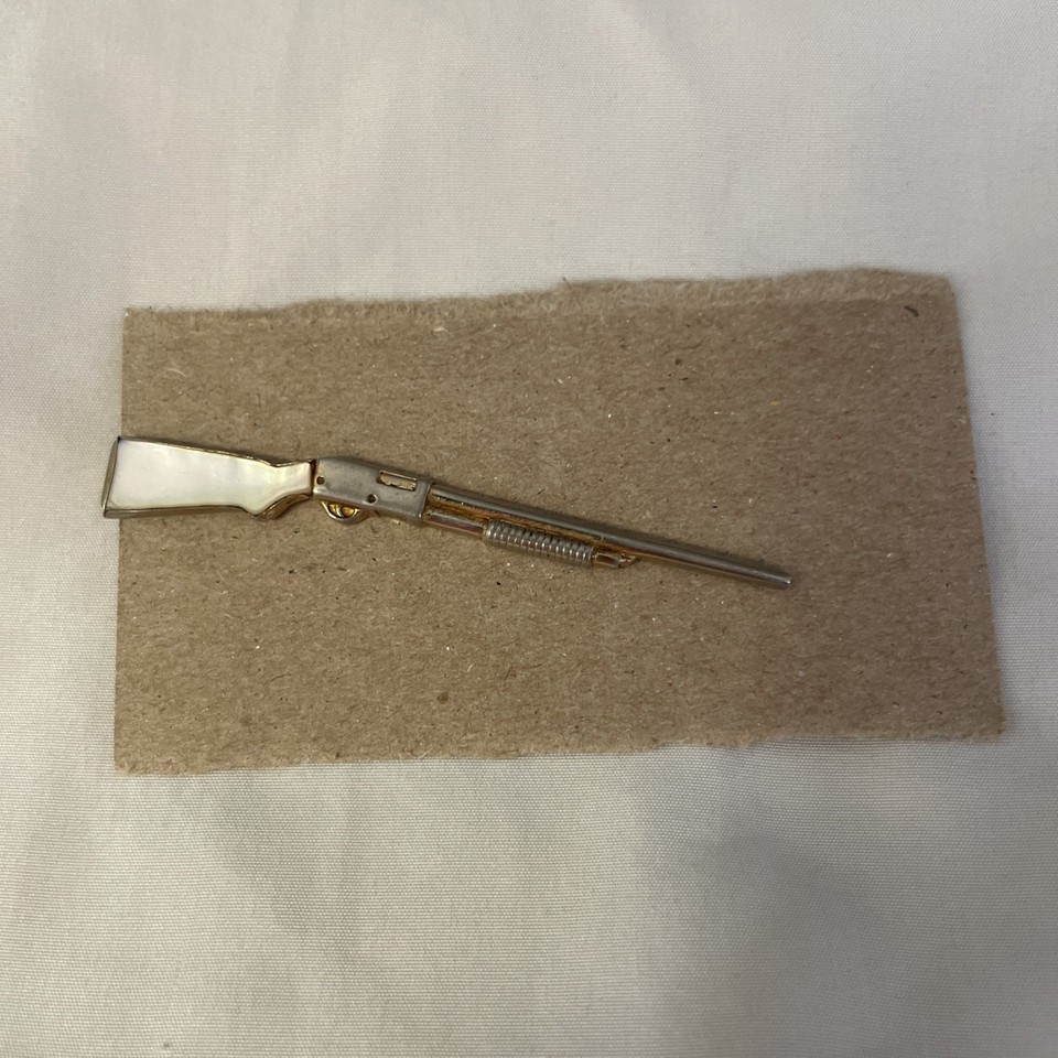 A vintage Swank tie clip shaped like a shotgun with a mother-of-pearl stock — a tiny, wearable piece of Americana that's equal parts dapper and audacious.