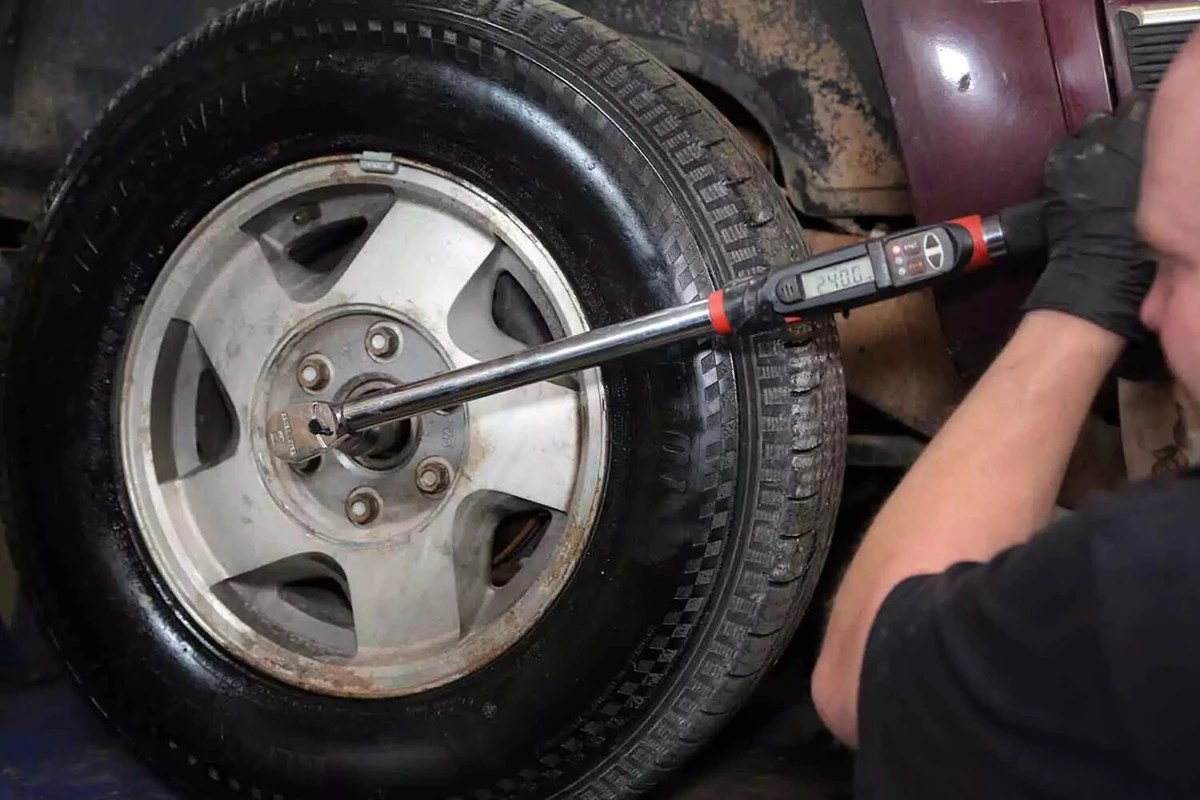 A mechanic tightens a lug nut with a torque wrench to factory specifications.