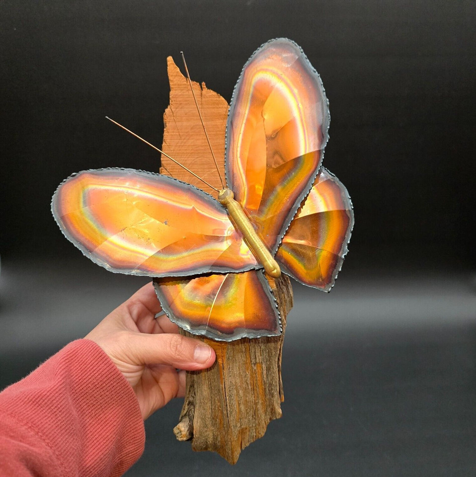 Brass and copper metal butterfly mounted on a wood branch — a sculptural mid-century wall piece with warm metallic charm that reads as art, not décor filler.