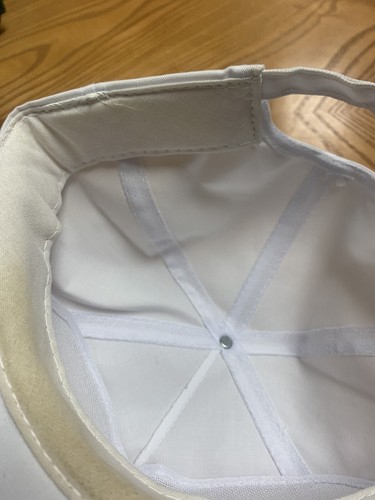 White vintage cap with green and yellow stitching, tan brim, and visible “Coop Seed” label on the interior.
