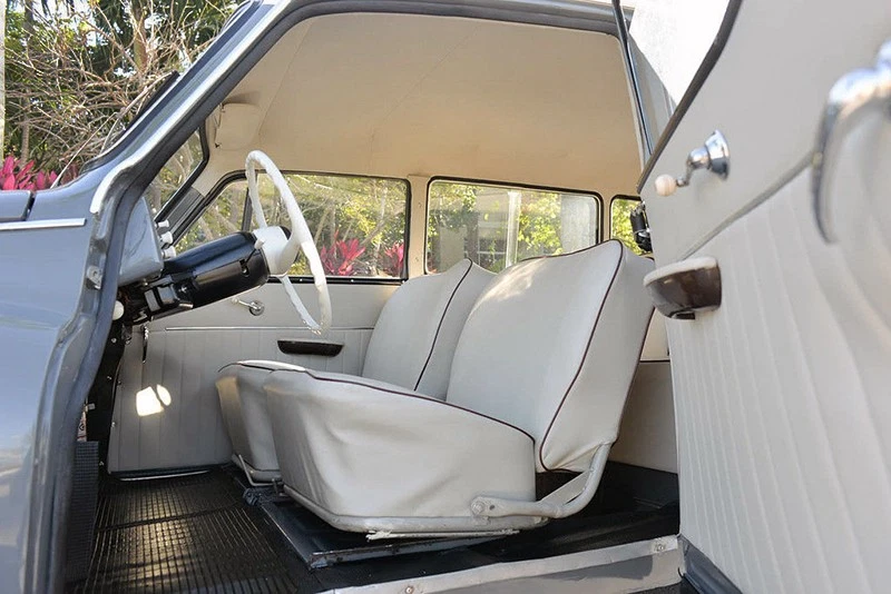 The suicide doors open to reveal white upholstery with red piping.