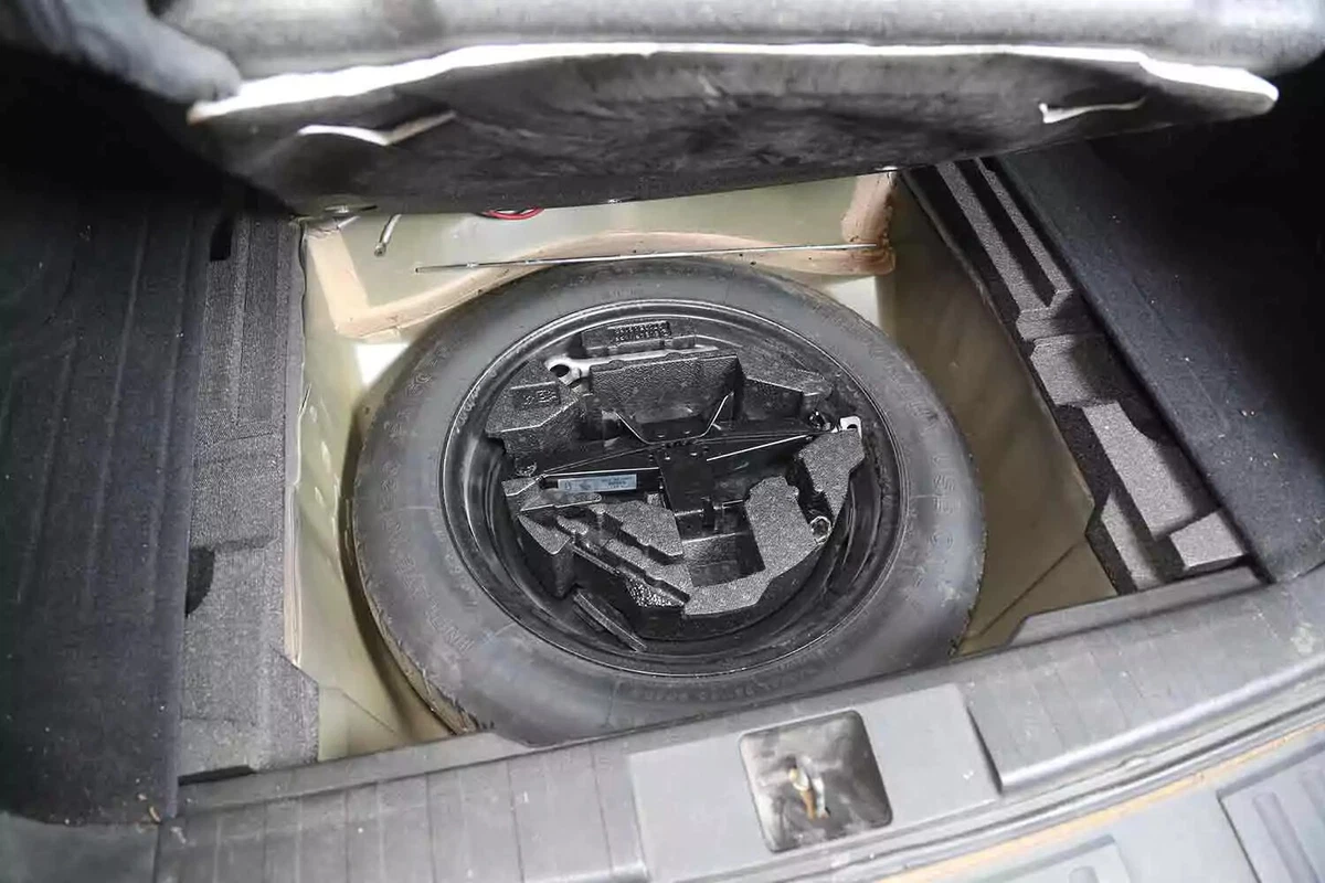 A spare tire and jack shown in a vehicle's trunk.