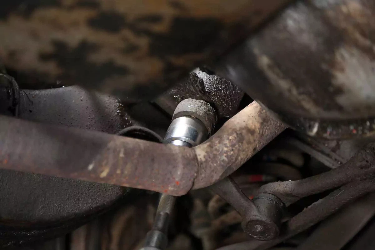A large socket and impact gun remove the pitman arm nut.