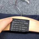 White fabric tag on blue jacket with red “Made in USA” text, machine wash warm, tumble dry low, no bleach, no iron.
