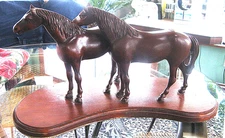 a pair of stunning hand carved wood horse statures the two are mounted on wood