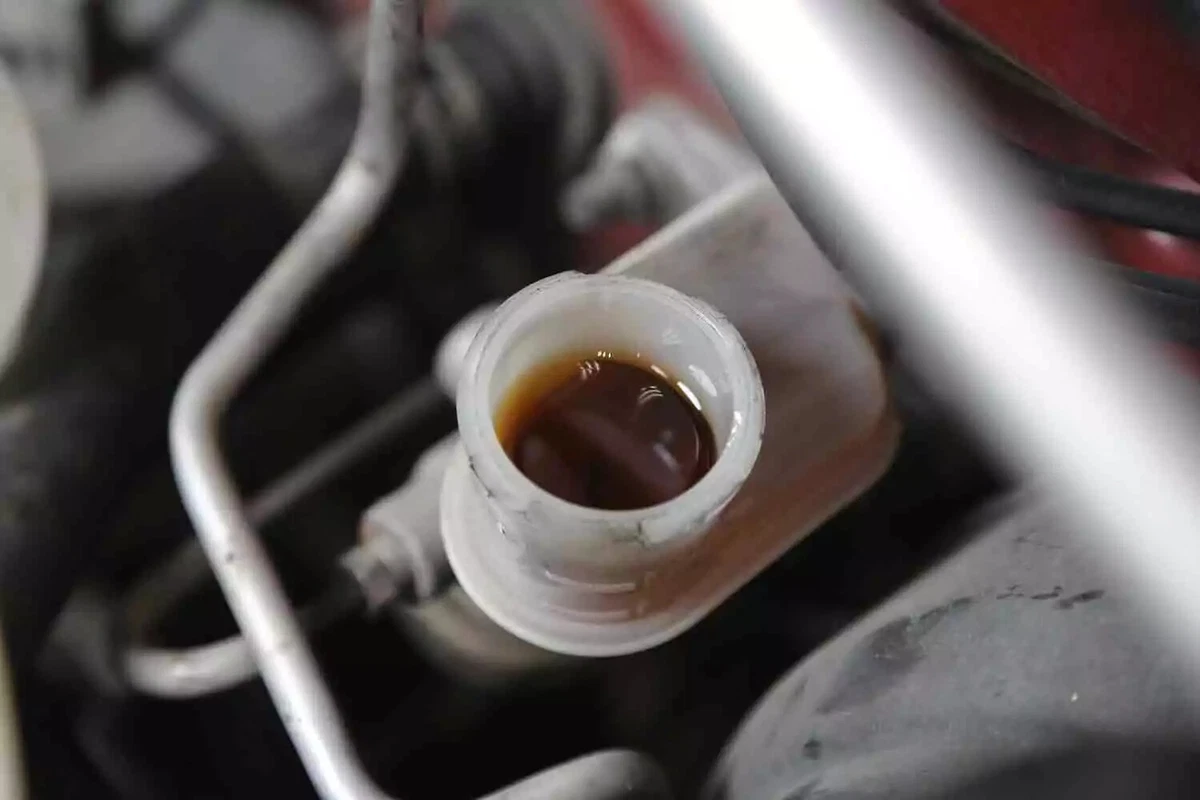 A clutch fluid reservoir filled with dark fluid, with the cap removed.