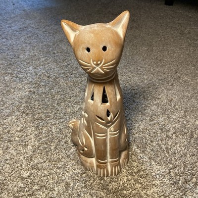 A Terracotta Cat With Cut Out Designs For Candles