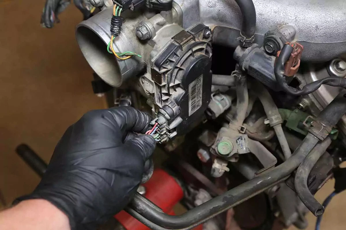 A mechanic reconnects the throttle body wiring.
