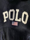 Navy fleece hoodie with cream text “POLO” and red, white, and blue American flag patch on chest.