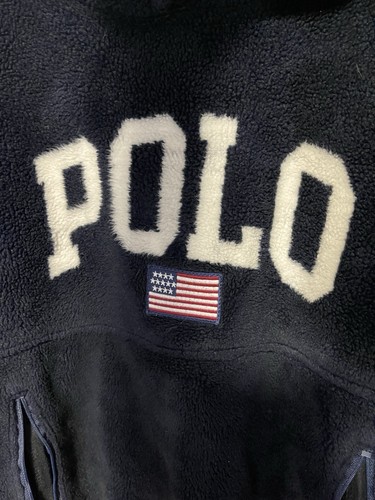 Navy fleece hoodie with cream text “POLO” and red, white, and blue American flag patch on chest.