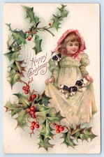 1909 Christmas Postcard- Girl Holding Puppies in Skirt of Dress-Sprigs of Holly