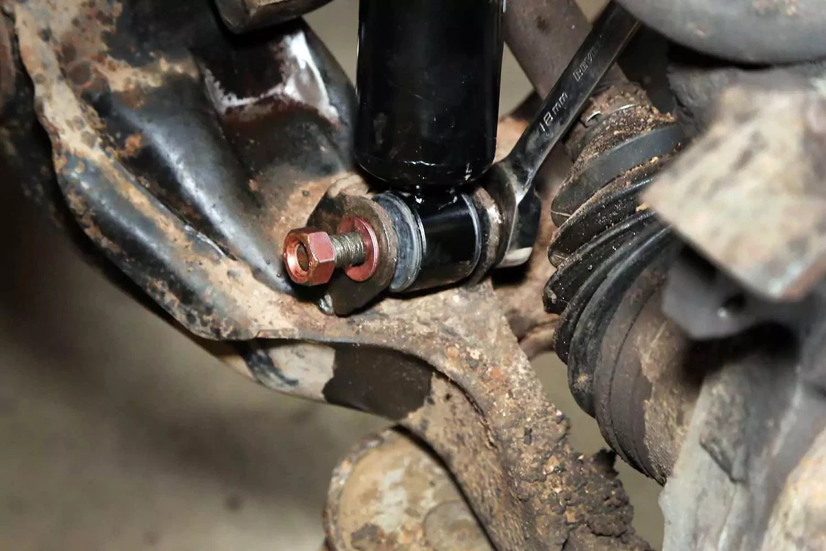 An open-end wrench is used to tighten the shock absorber’s lower fastener.