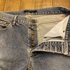 Blue stretch denim pants with 30x33 size, button fly closure, and “Theory” brand tag on waistband.