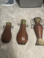 This is a set of distressed metal wall pocket vases with a red and bronze finish
