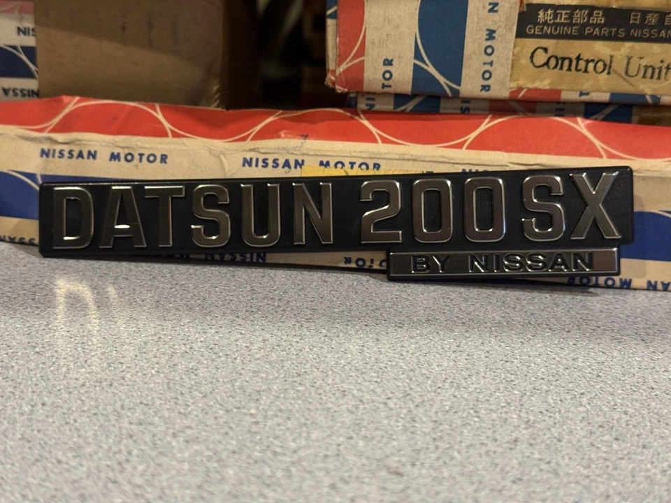 Insignia emblema Datsun 200SX 1979-1982 de Nissan Script NOS 84894-N8500 Foto 2 de 4
