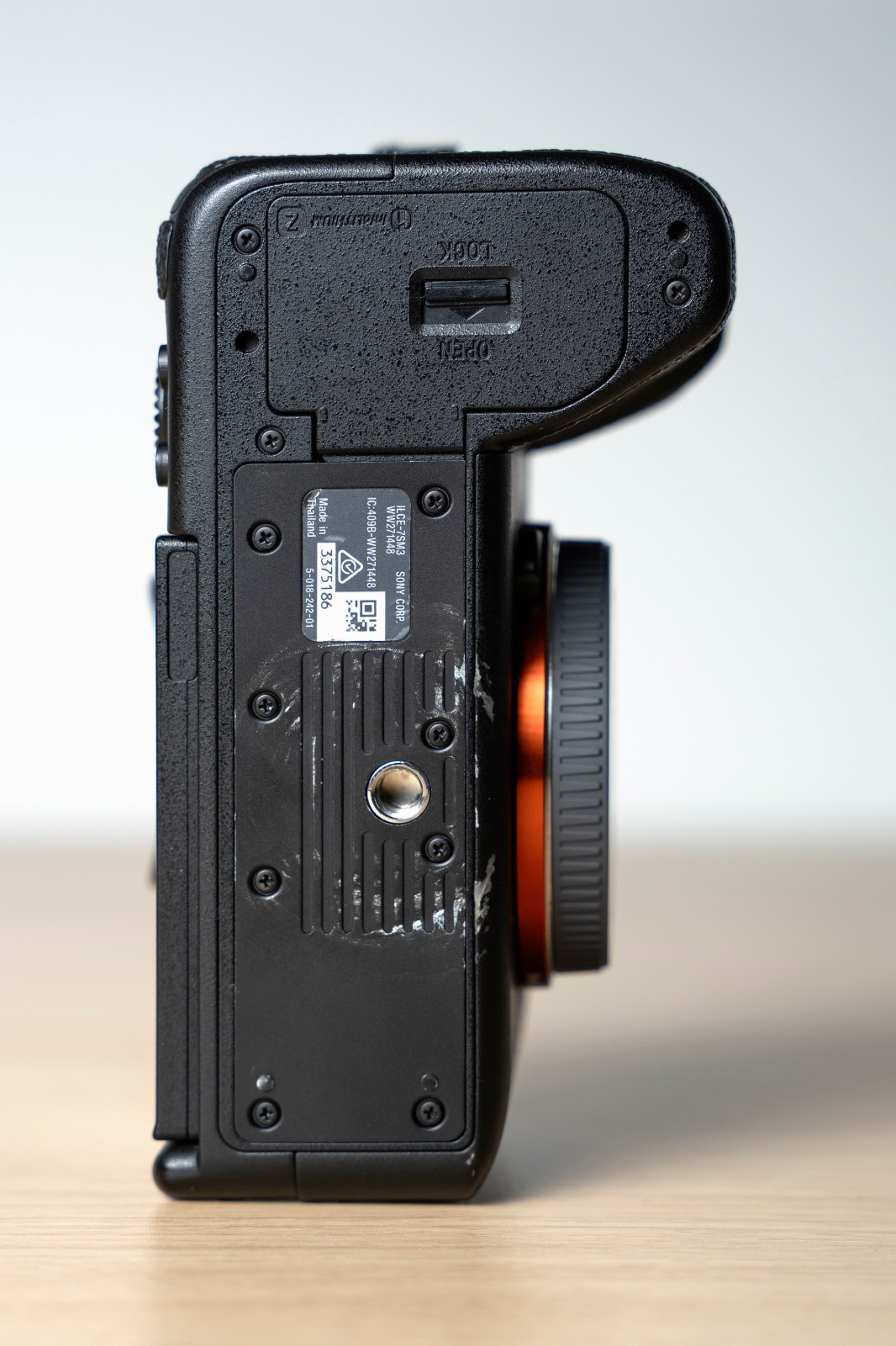 Black Sony Alpha a7S III camera back with two batteries, showing metal parts and engraved text on a wooden surface.