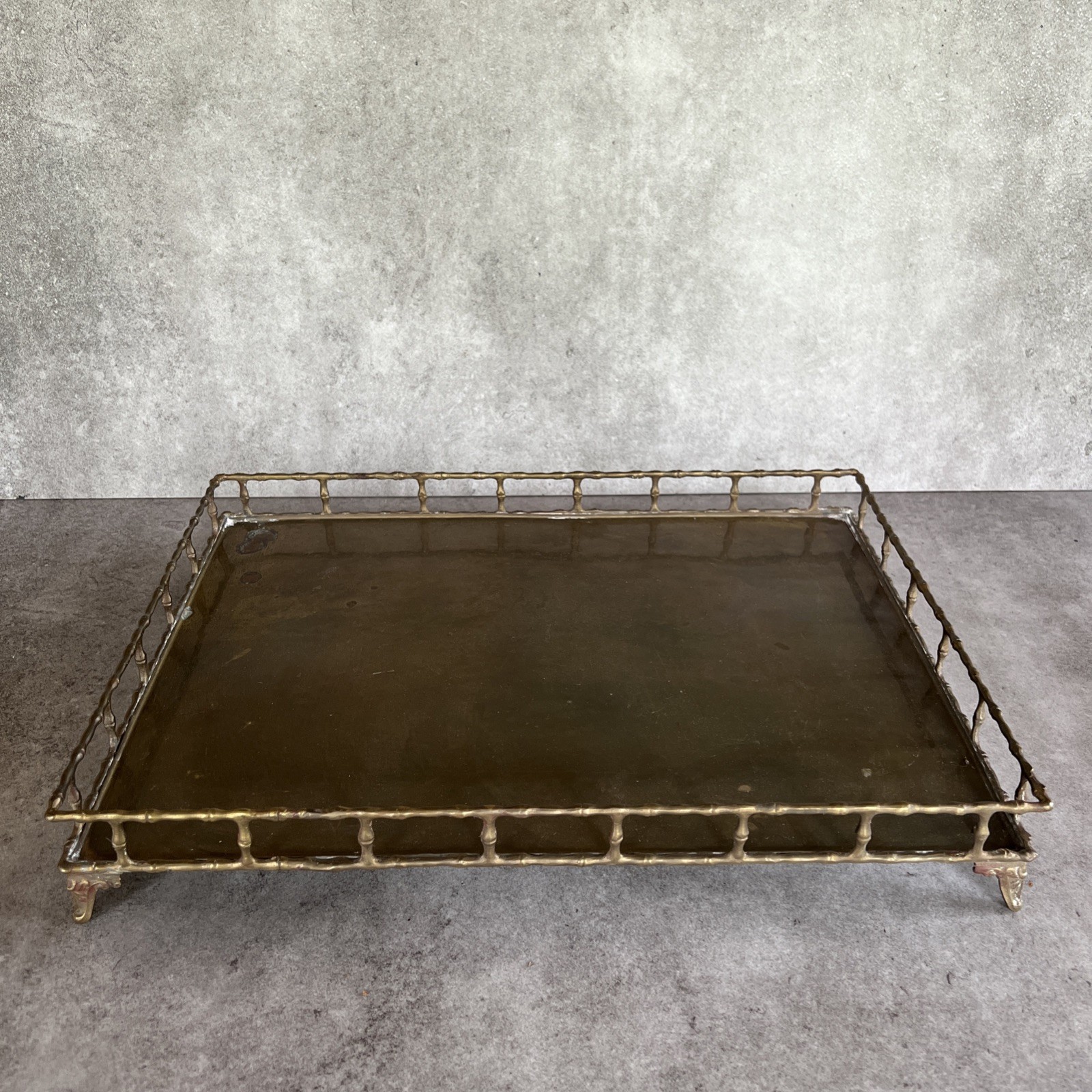 A large rectangular brass serving tray with a raised decorative rail border and side handles.
