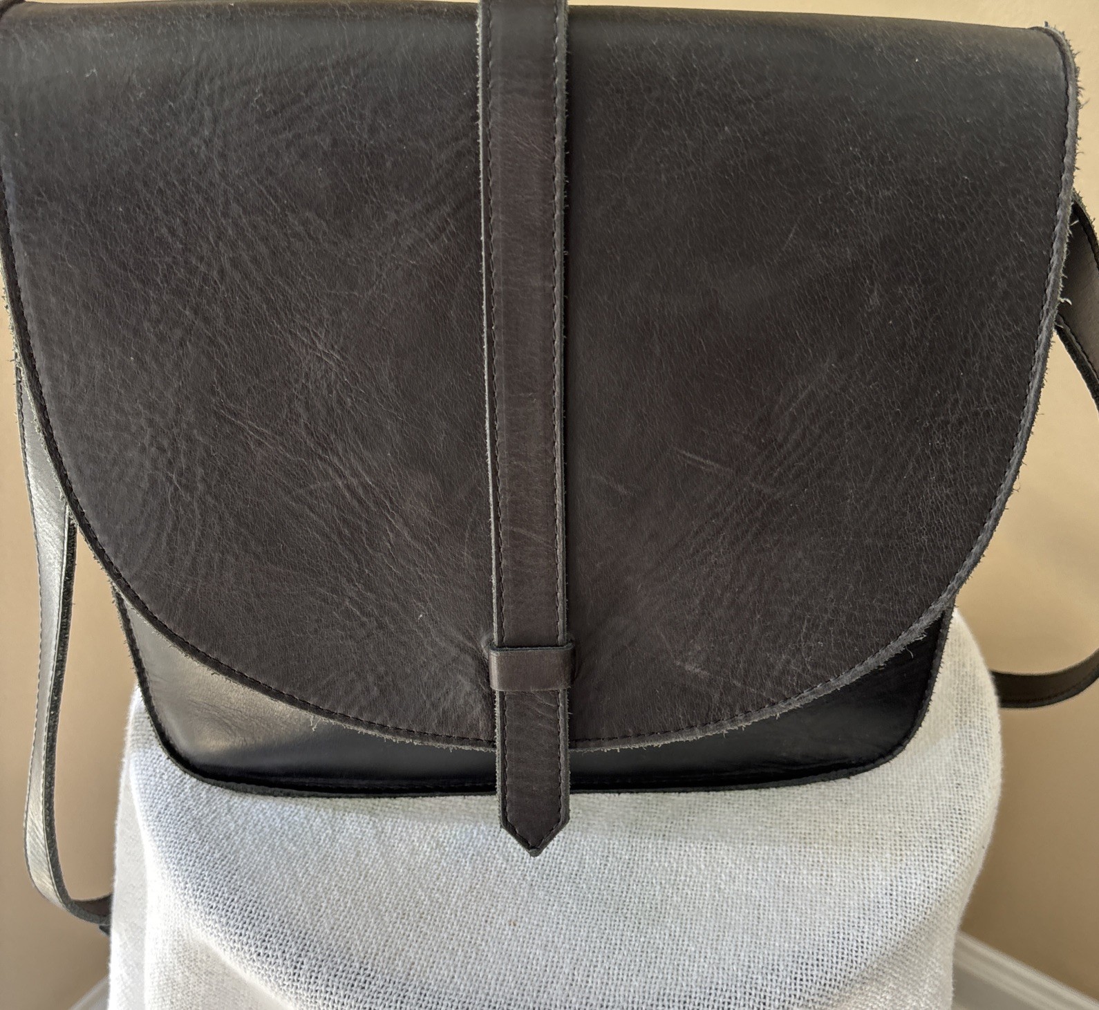 Black leather saddle bag with flap closure and adjustable strap.