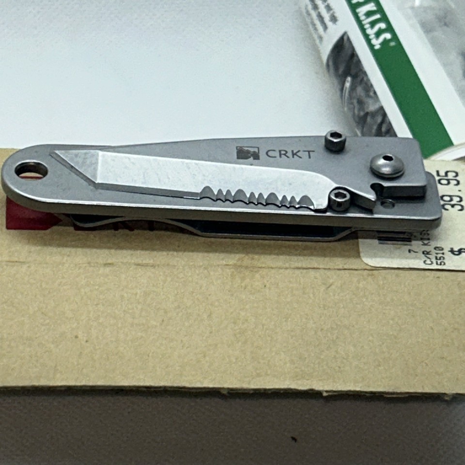A Y2K-era CRKT folding knife that doubles as a money clip — compact, clever, and comes with its original receipt for pure time-capsule energy.