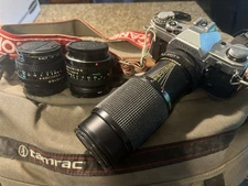 Canon AE-1 35mm SLR film camera with a telephoto lens. Tamarac Camera Bag.