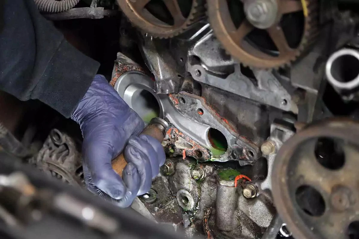 Mechanic cleaning the gasket off the engine block with a gasket scraper.