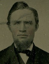 MAN WITH LOPSIDED HAIR. TINTED TINTYPE IN PERIOD PAPER MAT.