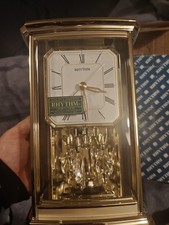 Rhythm Quartz mantel clock with a rotating pendulum and musical cherub figures.