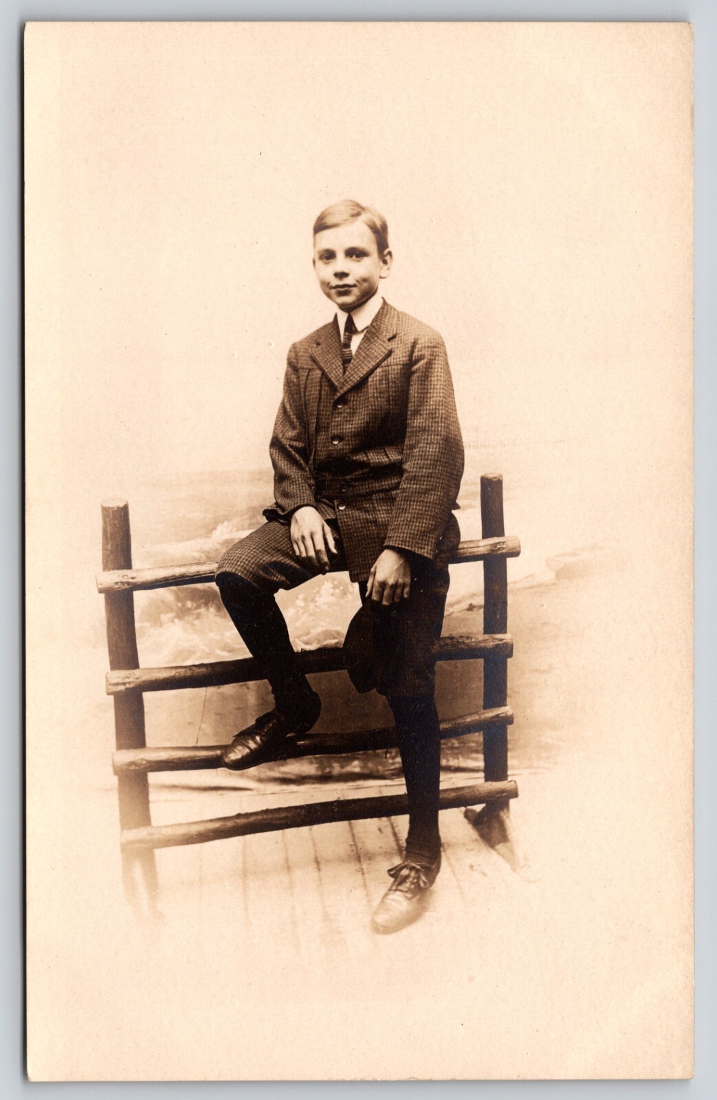 Postcard RPPC Young Man it Checkered Suit Sitting on Fence Real Photo