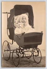 RPPC CLOSEUP~Darling Little Princess in a "Cadillac" of Strollers~Fur, Bows 1910