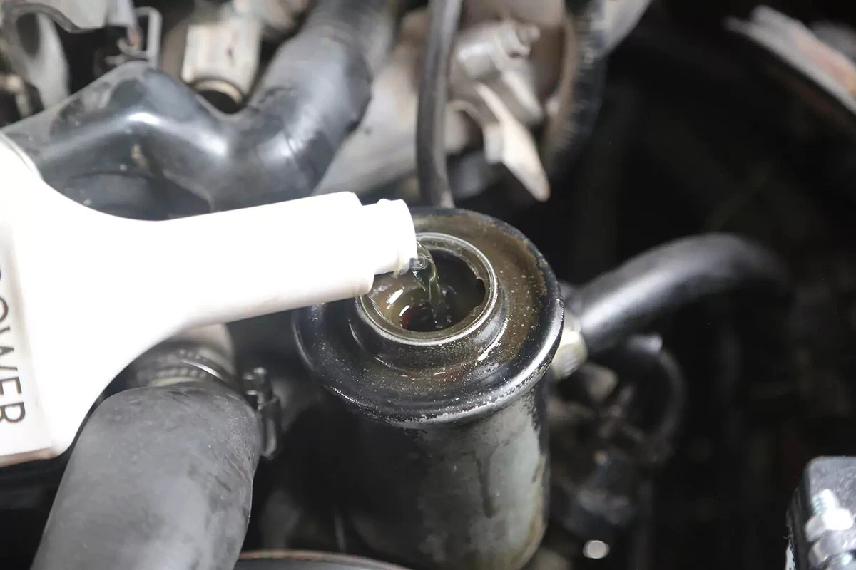 New power steering fluid being poured into the power steering reservoir of a vehicle.