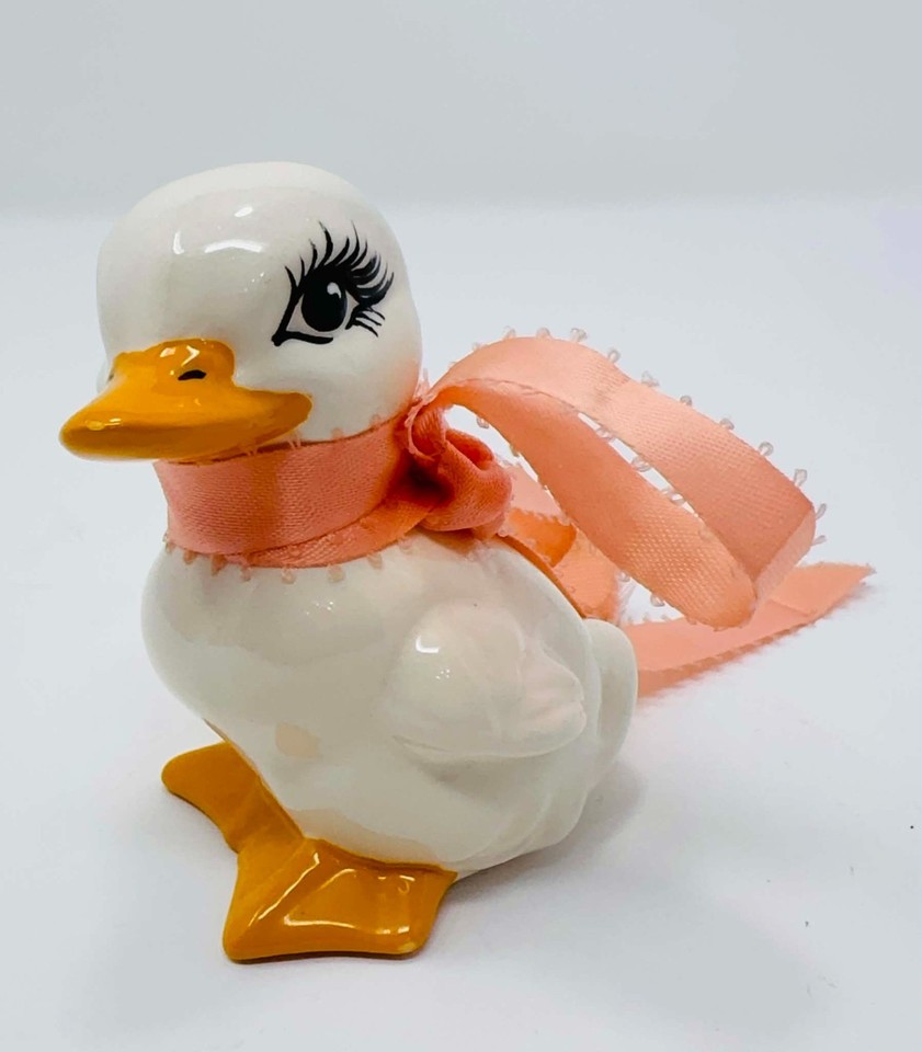 Glossy big-eyed ceramic duck with pink ribbon that straddles the line between kitsch and cottagecore charm — instantly lovable or hilariously awful depending on your taste.