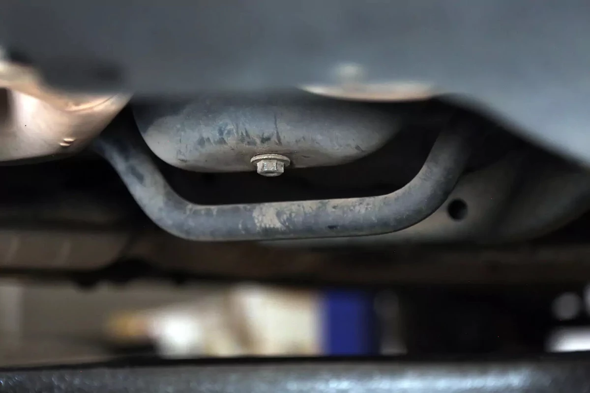 Oil pan with plug near a sway bar.