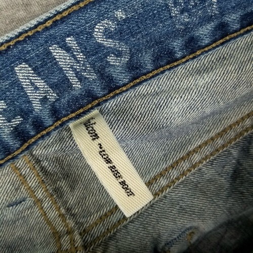 Blue distressed GUESS jeans 31 waist with faded thighs, front button fly, and white fabric tag with yellow printed text.