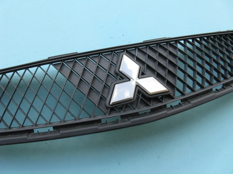 09 10 11 12 MITSUBISHI ECLIPSE ПЕРЕДНИЙ БАМПЕР КРЫШКА ВЕРХНЕЙ РЕШЕТКИ ЛОГОТИП Б/У OEM - Изображение 3 из 4