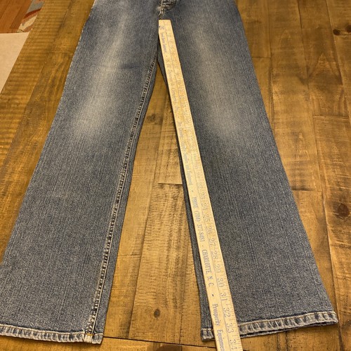 Blue Theory jeans, 30x33, with yellow measuring tape across the waistband, on wooden floor.