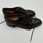 Black leather Johnston & Murphy Optima size 11 with closed lacing, brown insoles, and black laces on white background.